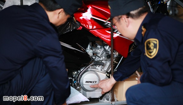 海關關員正在仔細核對涉嫌侵權(quán)摩托車的商標